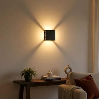 Arandela LED de quatro faróis preta iluminando uma sala com luz amarela.