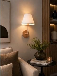 Luminária de parede minimalista rose gold e branco iluminando uma mesa com livros