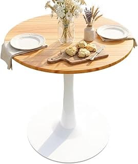 Mesa de jantar redonda pequena com tampo de madeira e base branca, decorada com pratos, biscoitos e flores.