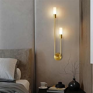 Lâmpada de parede dourada com design minimalista, iluminando um quarto com fundo cinza.