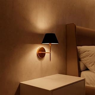 Arandela de parede dourada com cúpula preta iluminando quarto