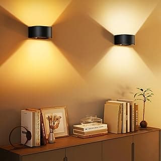 Luminárias de parede LED Tobeape, pretas, iluminando uma prateleira com livros e uma planta.
