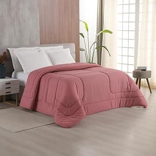 Edredom rosa matelado king size com acabamento acetinado, disposto sobre uma cama.