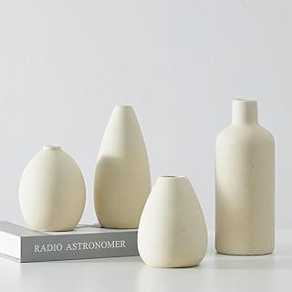 Conjunto de quatro vasos de cerâmica bege em um fundo branco, com um livro de astronomia ao fundo.