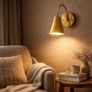 Arandela de parede industrial cone dourado iluminando sala com poltrona e mesa