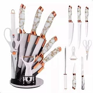 Conjunto de facas com cabos brancos e detalhes em cobre, dispostas em um suporte de aço inoxidável, fundo branco.