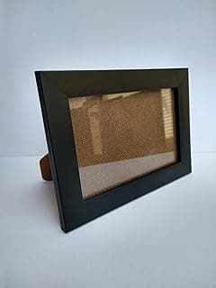 Porta-retrato preto 15x21 com moldura e acrílico, fundo bege, ângulo frontal.