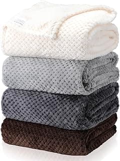 Três cobertores empilhados com cores branca, cinza claro, cinza médio e marrom, textura de waffle macia.