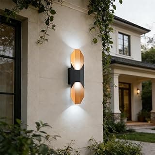 Arandela de parede preta e dourada iluminando a fachada de uma casa