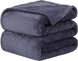 Três cobertores de cama roxos empilhados em uma pilha, mostrando a textura do tecido.