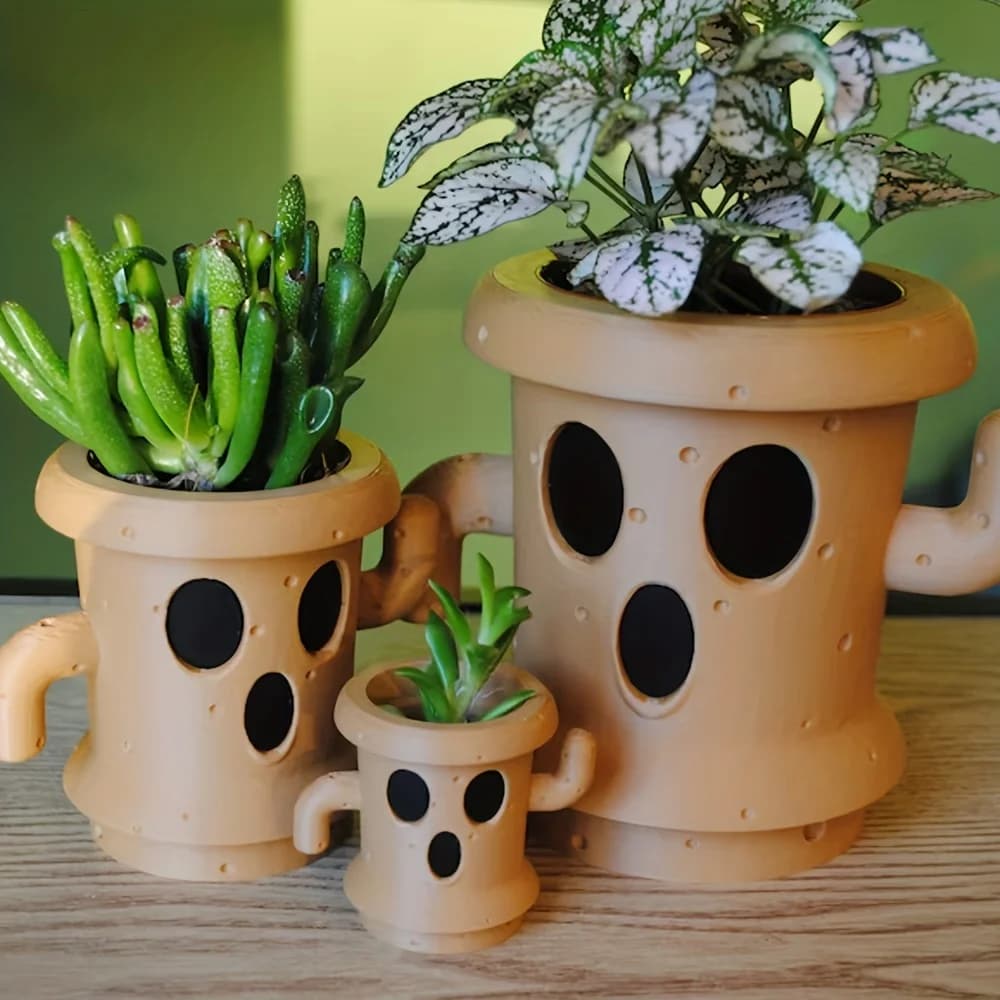 Trêas vasos de plantas em forma de monstro com olhos e buracos para ventilação. Cor marrom.