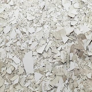 Fragmentos de material branco e cinzento, possivelmente restos de papel, superfície irregular