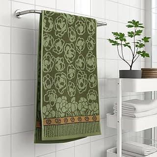 Toalha de banho verde com estampa floral em fundo claro, pendurada em suporte metálico.