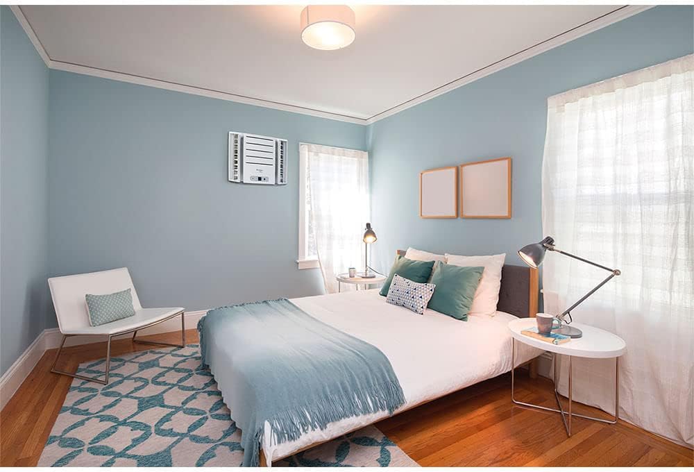 Quarto com ar condicionado de janela Springer Midea instalado, parede azul clara e decoração moderna.