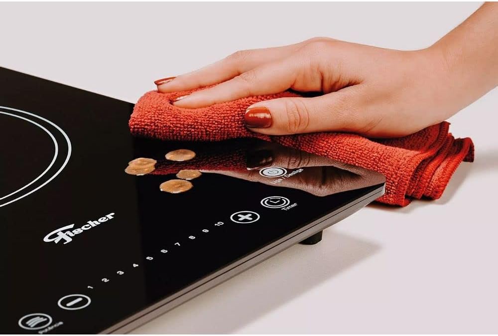Limpeza de cooktop indução Fischer preto com pano vermelho mostrando facilidade e praticidade