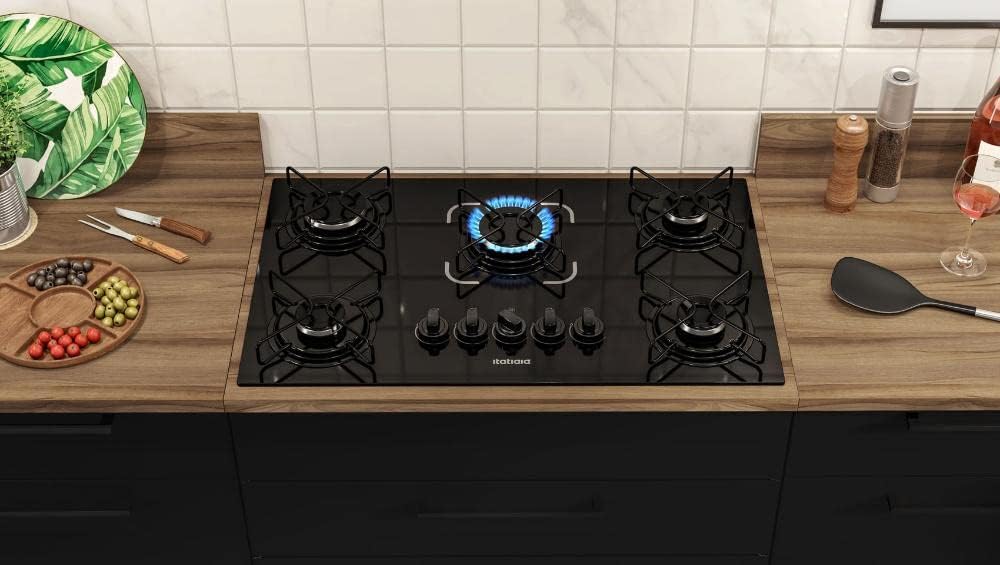 Cooktop Essencial preto 5 bocas instalado em bancada de madeira com chama acesa
