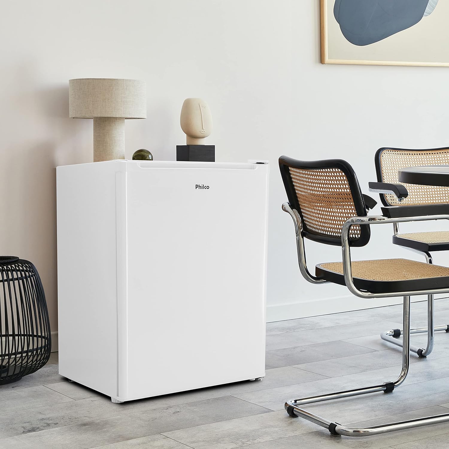 Frigobar Philco PH85N 68L branco em ambiente moderno ao lado de cadeiras e decoração